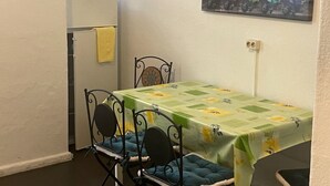 Un pequeño comedor con una mesa y sillas, un refrigerador y un extintor en la pared.