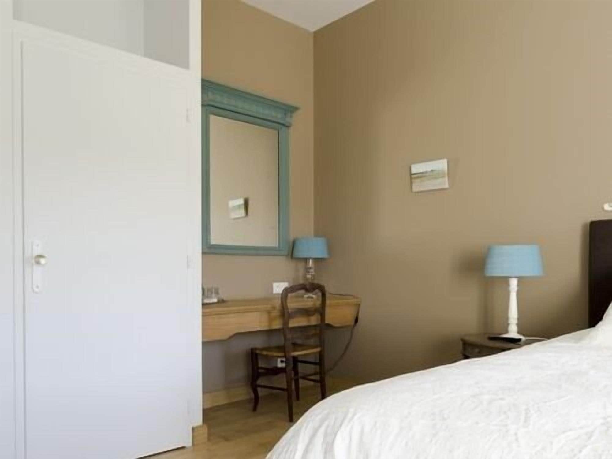 Une chambre à coucher comprenant un lit, un bureau, une chaise et deux lampes de chevet.