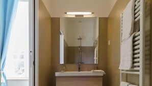 Un baño con ducha, lavabo y toallero.