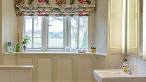 Un baño con ventana, lavabo y artículos de aseo.
