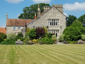 A stone house with a sloped roof, multiple windows, and a well-maintained lawn. - Old Church Farm (Bristol)