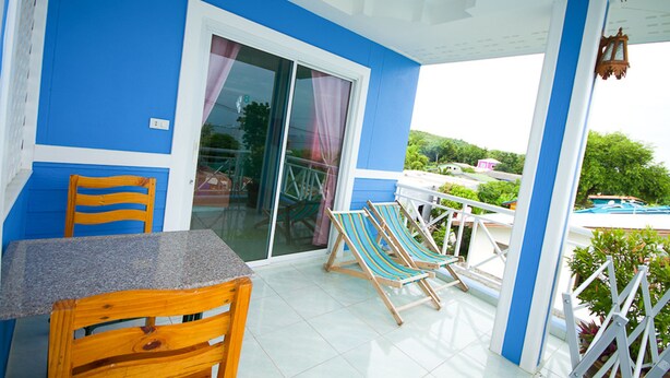 Una habitación azul y blanca con una mesa y sillas, un divisor corredizo de vidrio y vistas a una piscina.