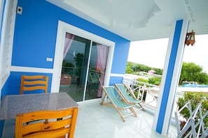 A blue and white room with a table and chairs, a sliding glass door, and a view of a pool. - BaanHappyLove (Koh Lan)