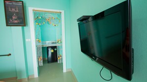 Una habitación con paredes verde azulado, un televisor montado, un cuadro enmarcado y un acceso decorativo.