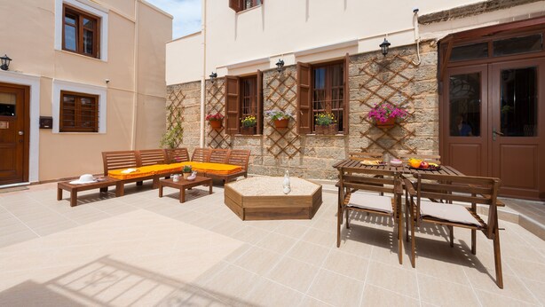 An outdoor patio with wooden furniture, a stone wall, and flower boxes.