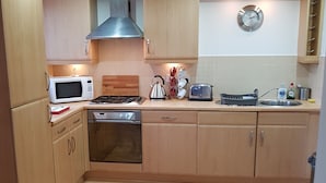 Eine moderne Küche mit Holzausstattung, einer Edelstahl-Dunstabzugshaube, einer Mikrowelle, einem Toaster und einem Spülbecken.