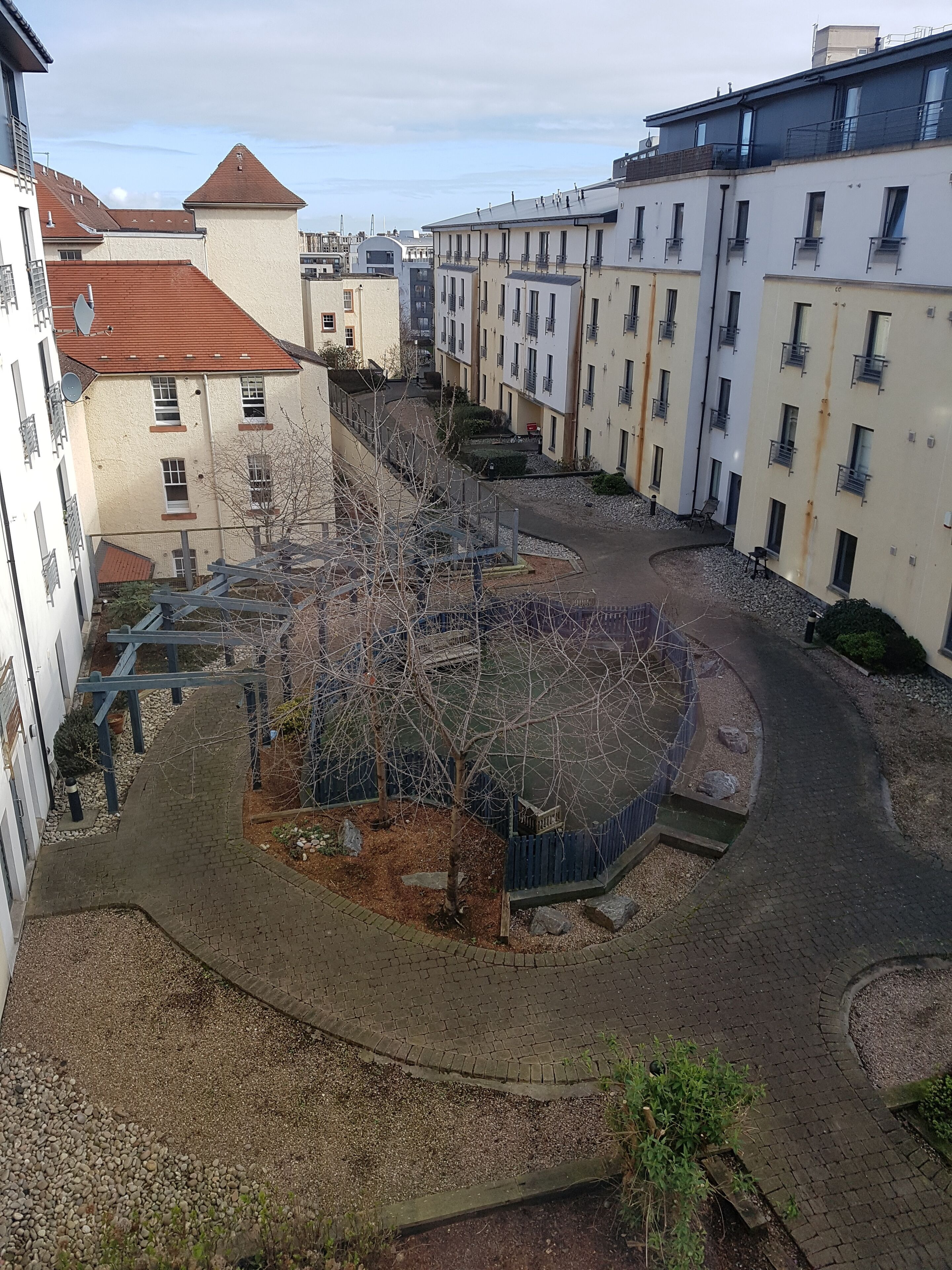 A courtyard with a central fountain, surrounded by multi-story buildings with balconies.