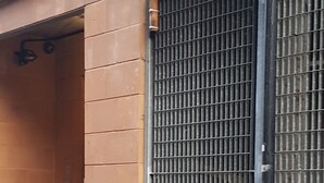 Ein Gebäudefassaden mit geschlossenem Metallgitter, einer Betonstütze und einem mit Fliesen belegten Boden.