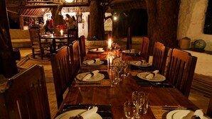 A dining area with wooden tables and chairs, candles, and a rustic ambiance.