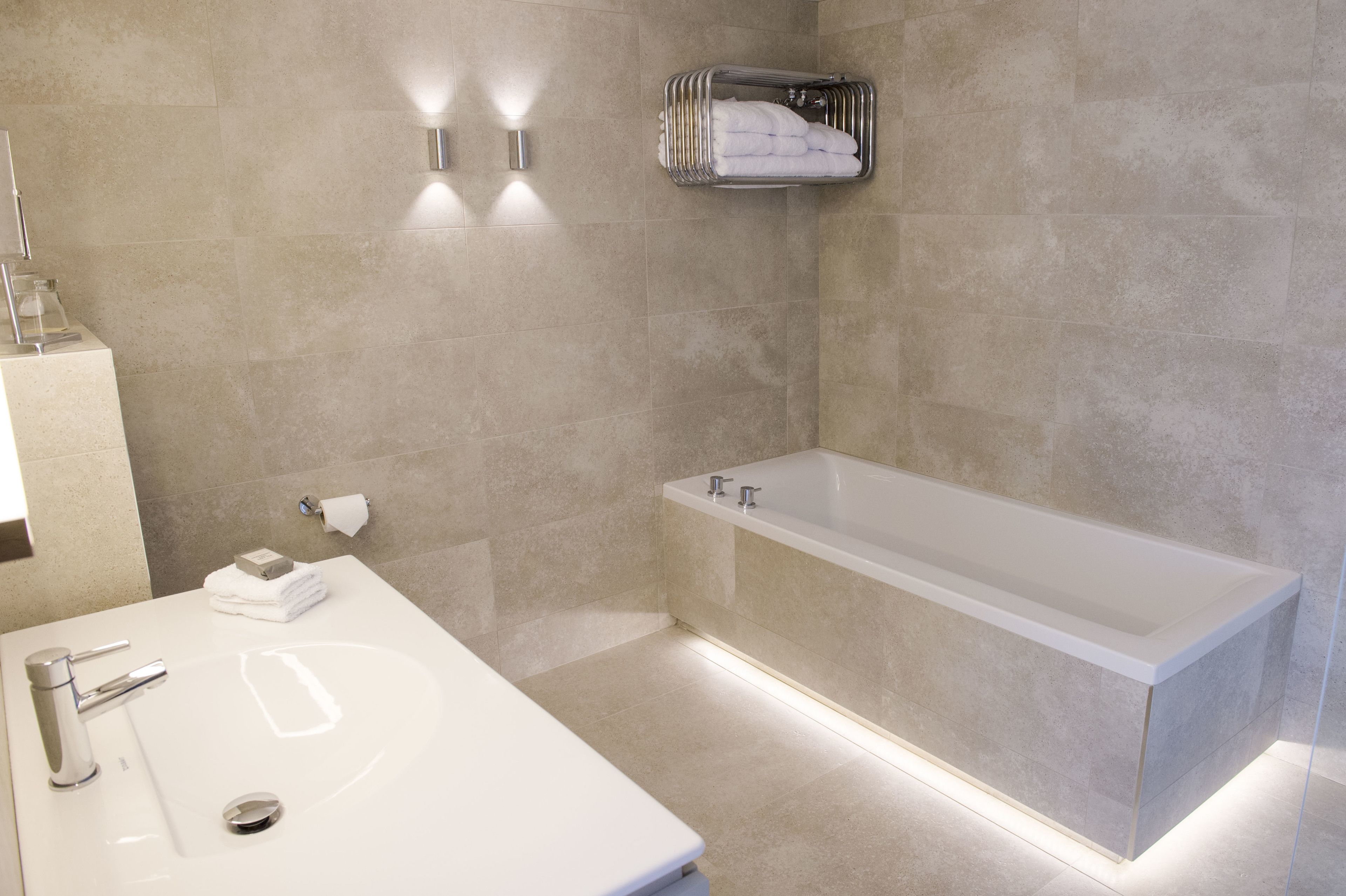 Ein modernes Badezimmer mit einer großen Badewanne, einem Waschbecken und einem Handtuchhalter.