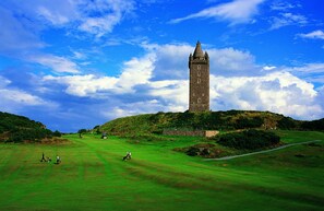 A historic tower on a hill with a golf course in the foreground. - Peartree Hill (Belfast)