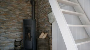 Ein modernes Interieur mit Kaminofen, Korbwäsche und einer weißen Treppe.
