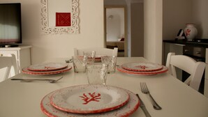 Een eettafel gedekt met borden, glazen en bestek, met een televisie en decoratieve items aan de wanden.