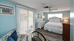 A bedroom with a bed, a nightstand, a chair, a ceiling fan, and a window with blinds. - The Seashell. Private Home #54561 3 Bedrooms 2 Bathrooms Home (Holmes Beach)