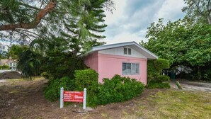 A small pink building with a sign indicating it is a vacation rental. - The Seashell. Private Home #54561 3 Bedrooms 2 Bathrooms Home (Holmes Beach)