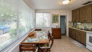 A compact kitchen with wooden cabinets, a dining table with chairs, and a window with blinds. - The Seashell. Private Home #54561 3 Bedrooms 2 Bathrooms Home (Holmes Beach)