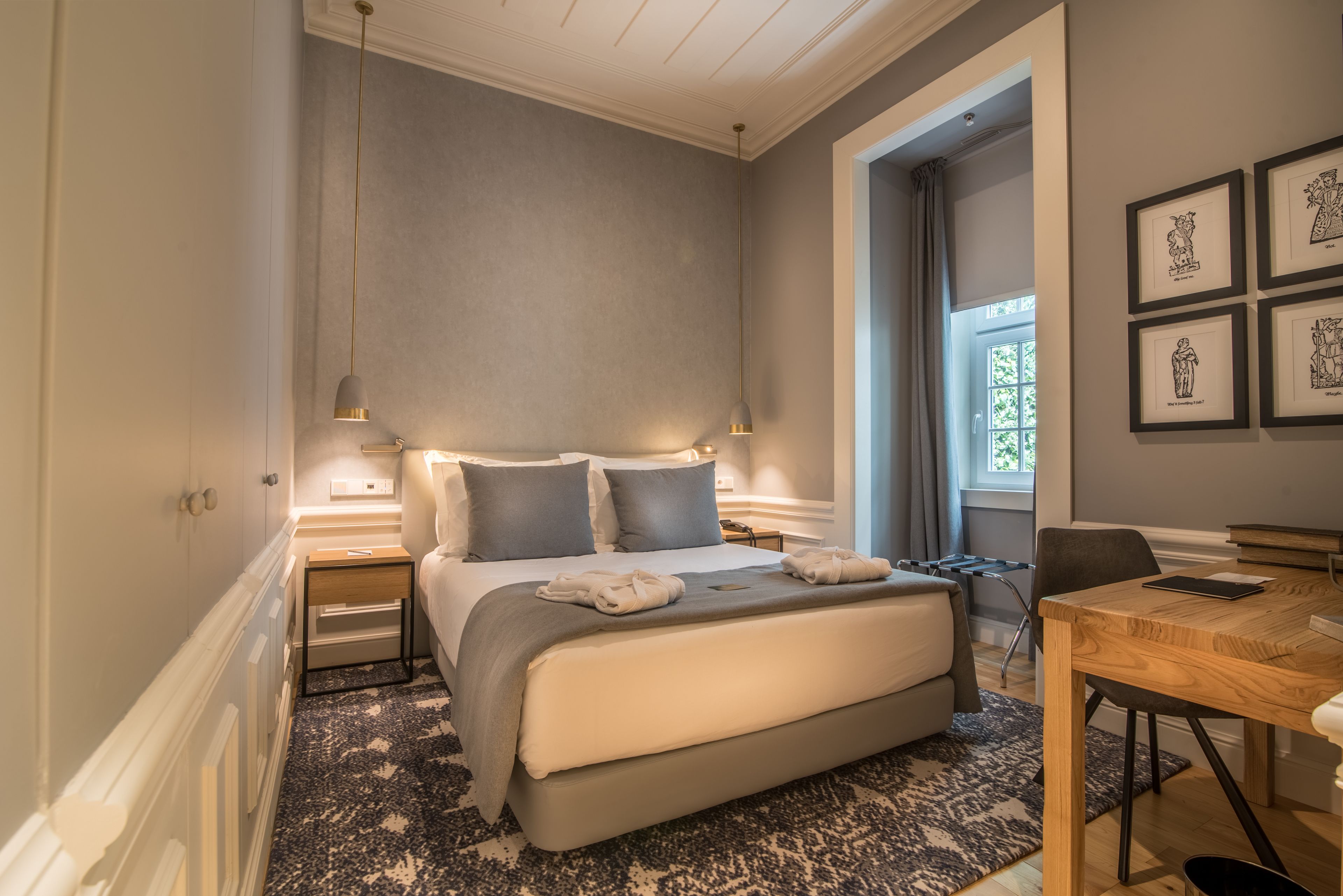 Un dormitorio con cama, mesitas de noche, un escritorio y una ventana.