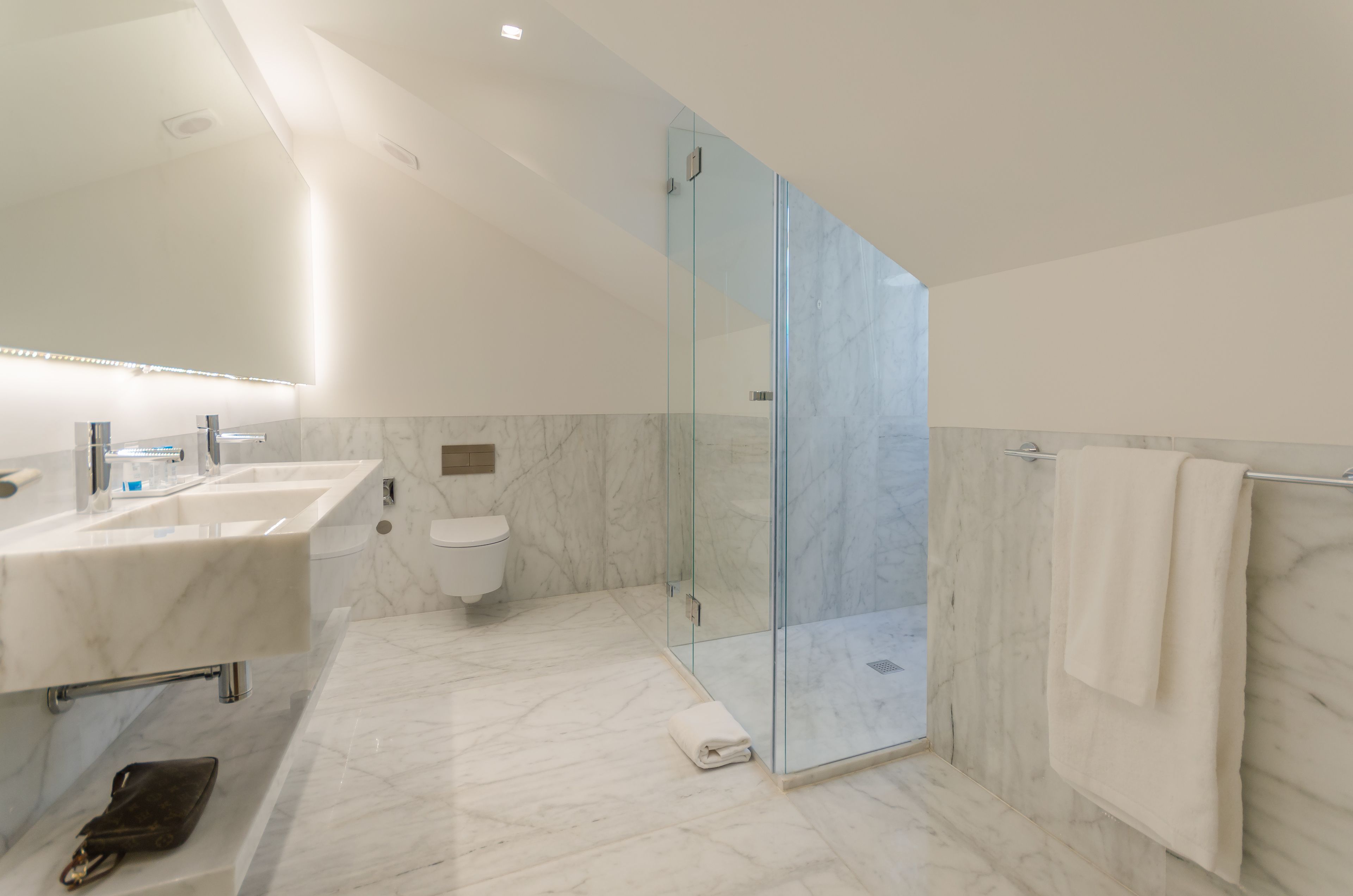 A modern bathroom with two sinks, a toilet, and a glass-enclosed shower.