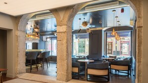 Ein modernes Interieur mit Säulen aus Stein, Sitzbereichen und einer Bar.