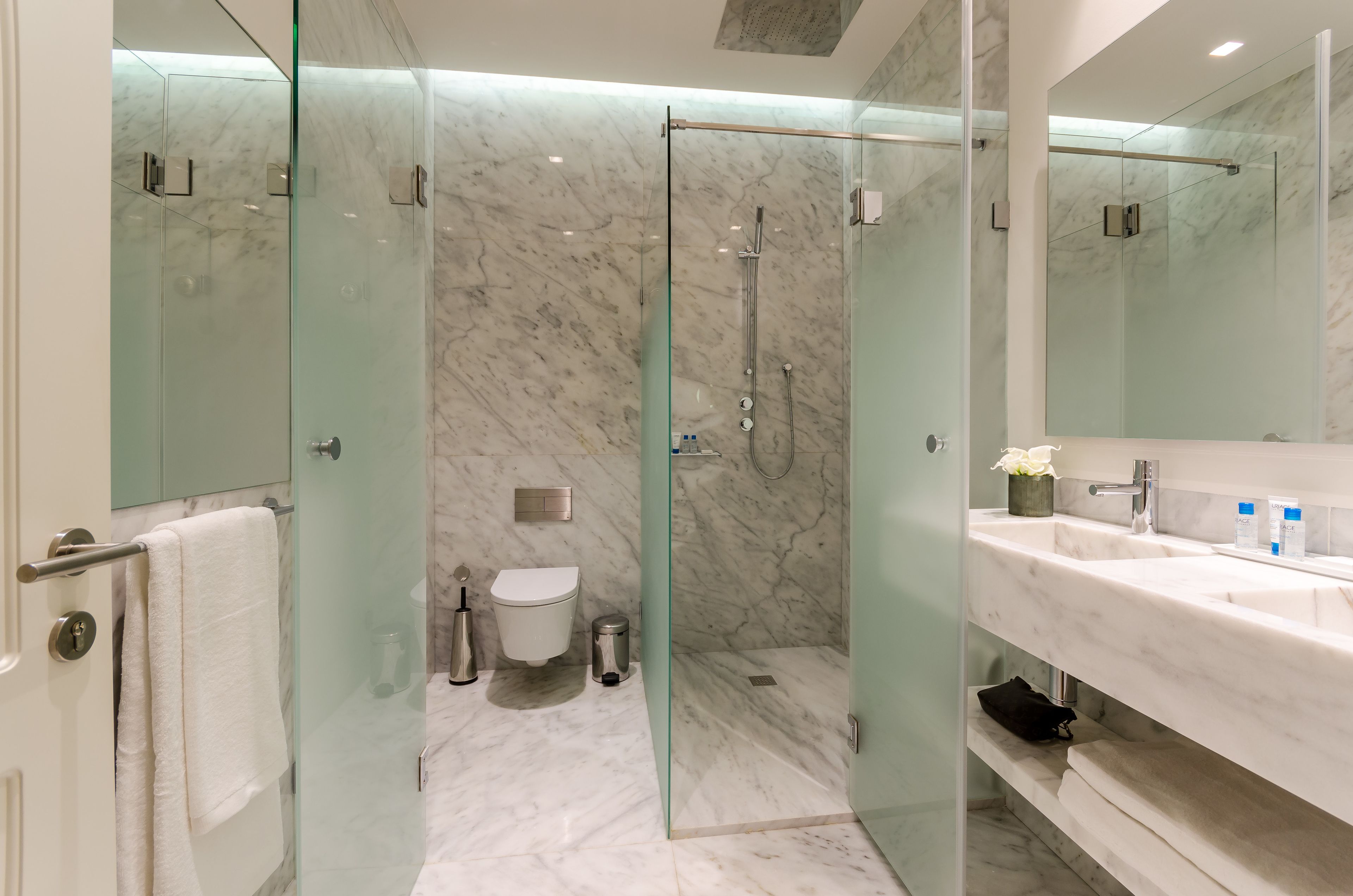 A modern bathroom with a glass-enclosed shower, a white toilet, and a vanity with a mirror and sink.