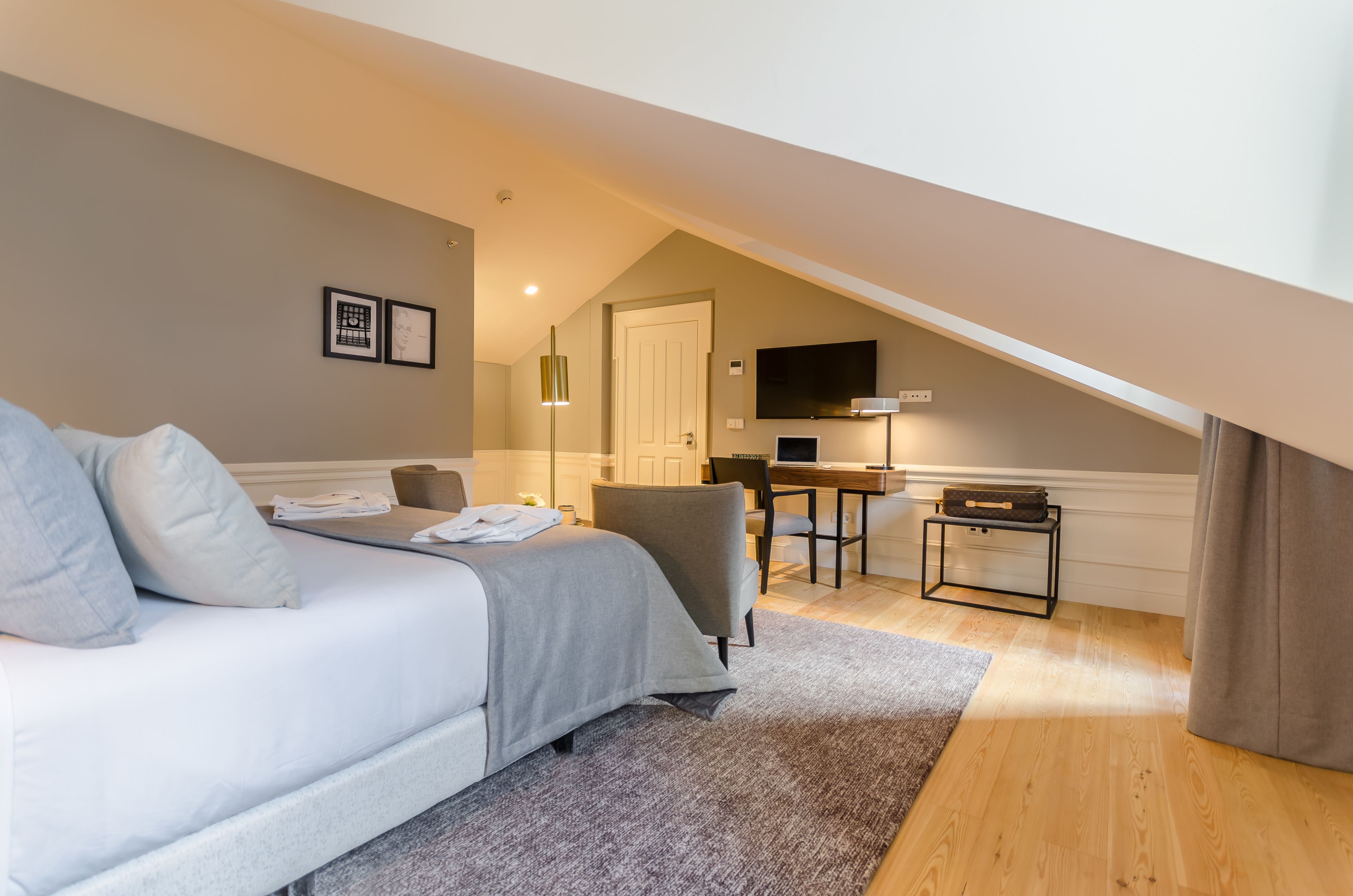 A bedroom with a bed, a desk, and a TV.