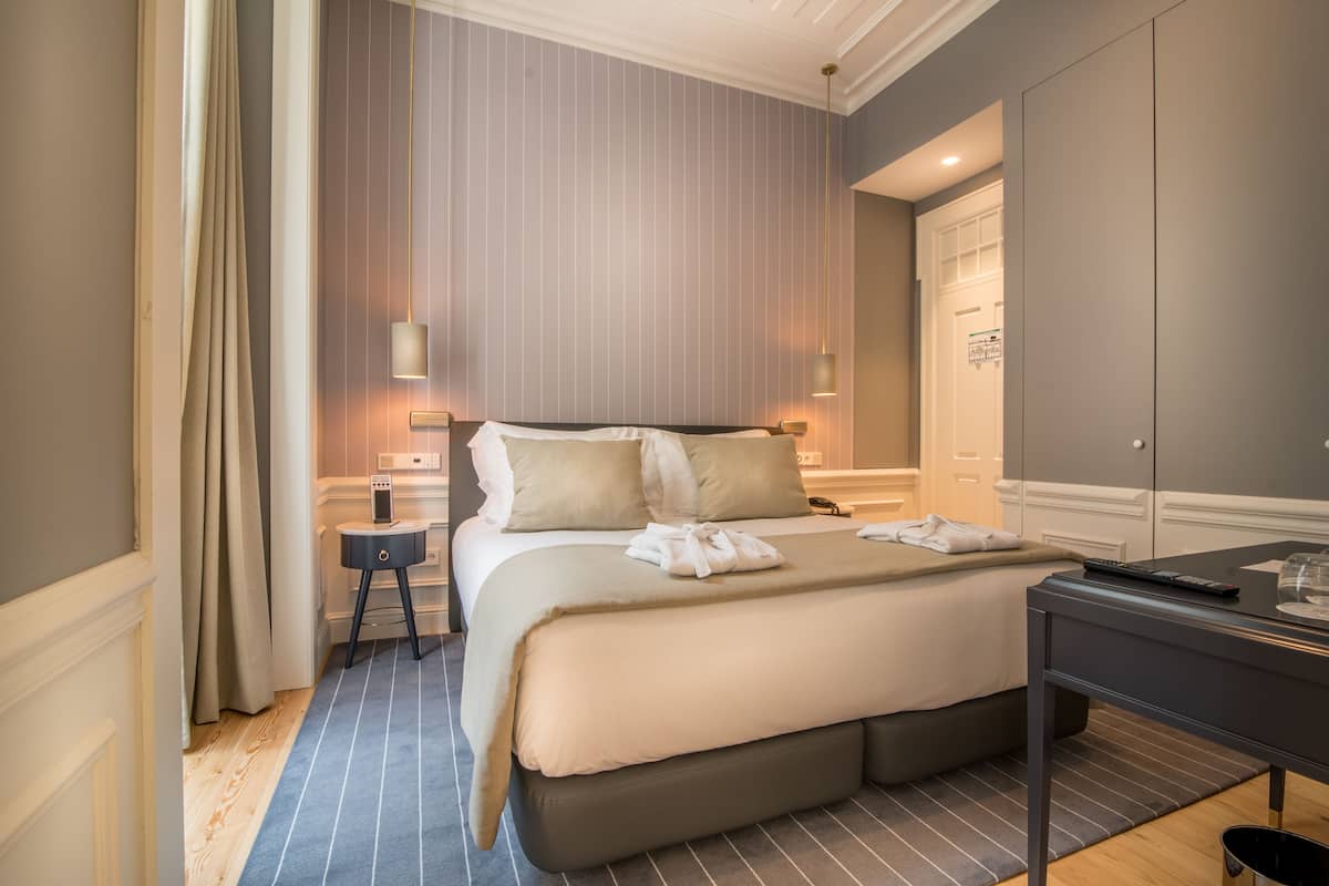 Una habitación de hotel con una cama grande, mesitas de noche, un escritorio y un armario.