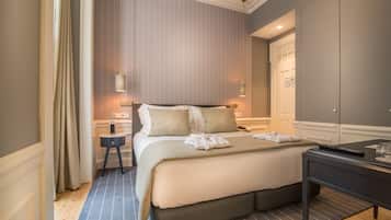 A hotel room with a large bed, bedside tables, a desk, and a wardrobe.