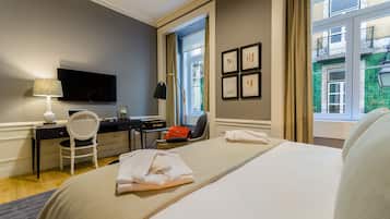A hotel room with a bed, desk, chair, and a TV.