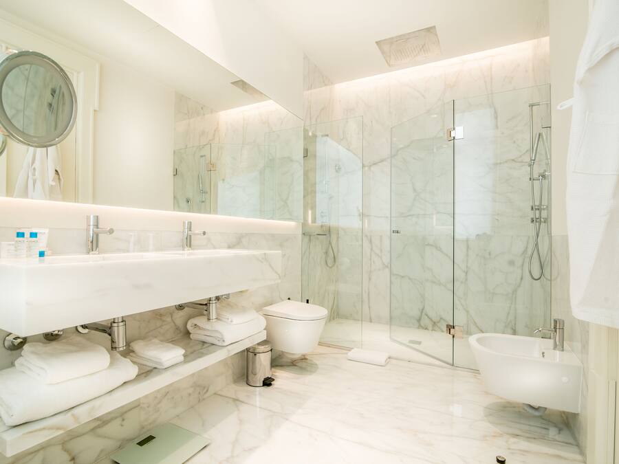 Un bagno moderno con lavabo in marmo, un water, un bidet e una cabina doccia in vetro.