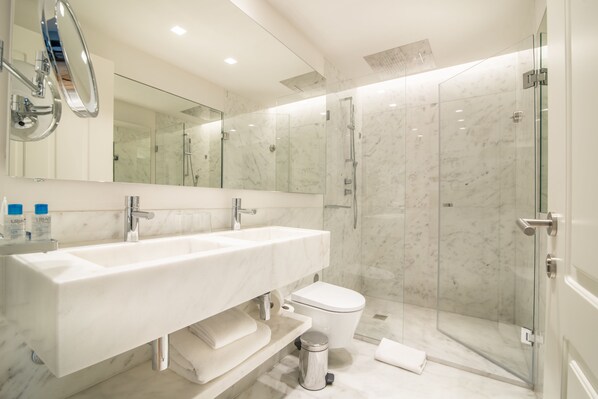 Un baño moderno con un lavamanos grande, un inodoro y una ducha con mampara de vidrio.
