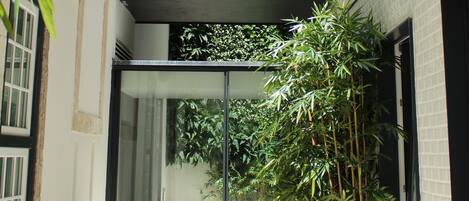 Un edificio moderno con fachada de vidrio, un jacuzzi pequeño al aire libre y follaje circundante.