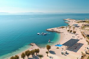 An aerial view of a coastal area with a beach, a pier, and a solar-powered structure. - Sun Spalato Views (Split)