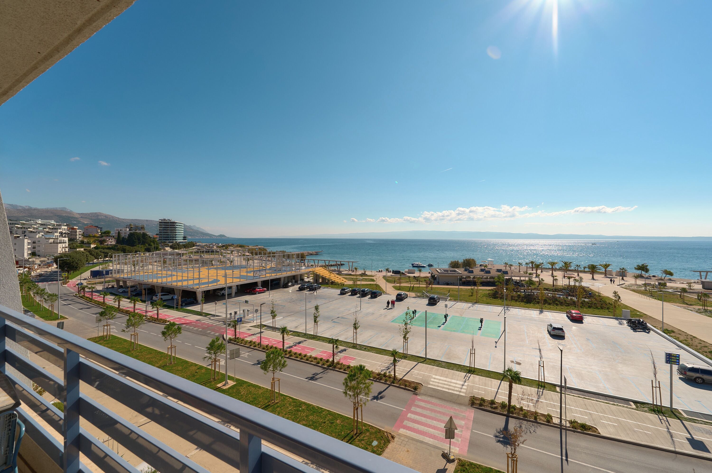 A parking lot with a view of the sea and mountains in the background.