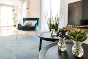 Un salon moderne avec un canapé, deux vases contenant des plantes succulentes et un téléviseur.