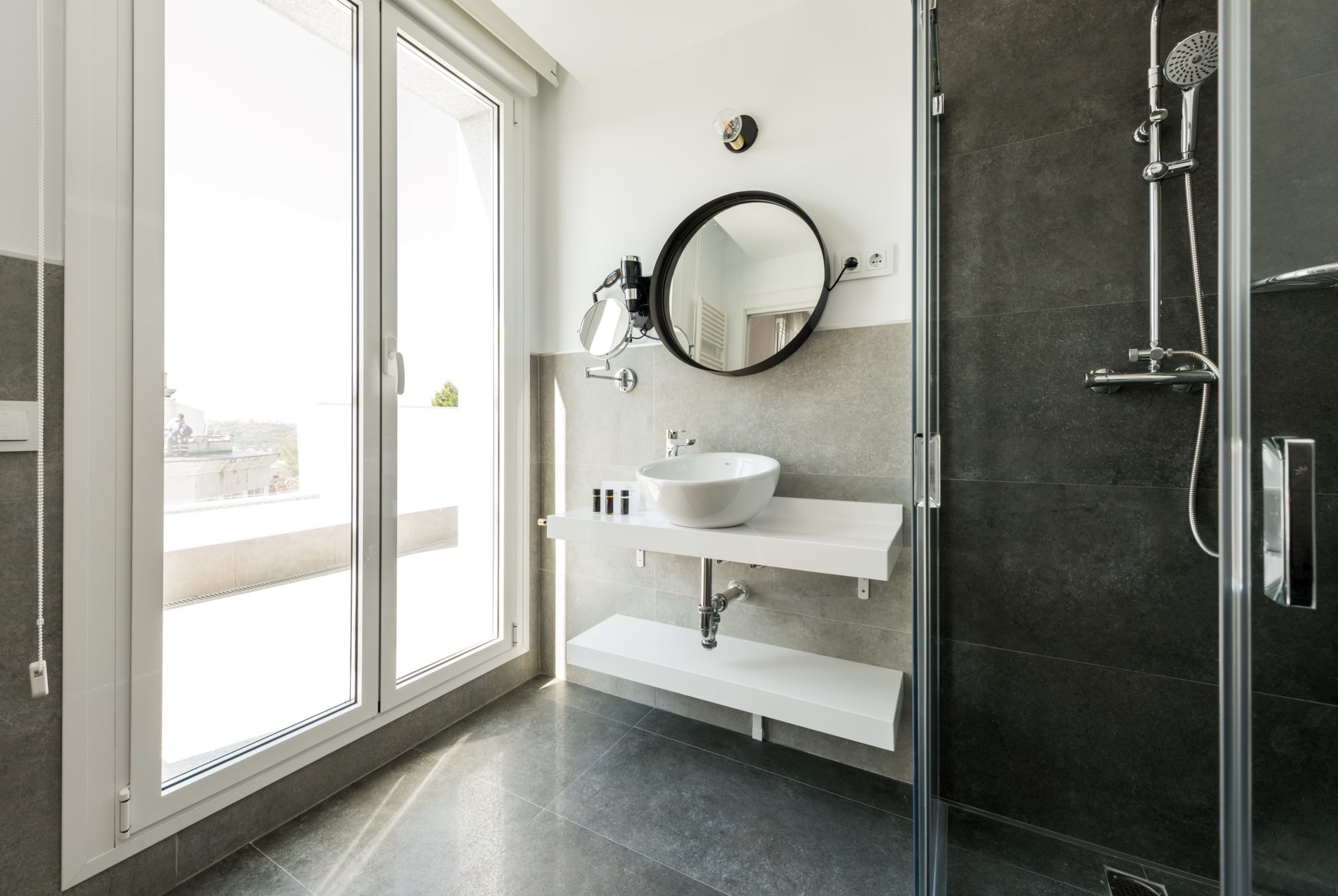 Une salle de bain moderne avec une douche à parois de verre, un lavabo blanc et un grand miroir.