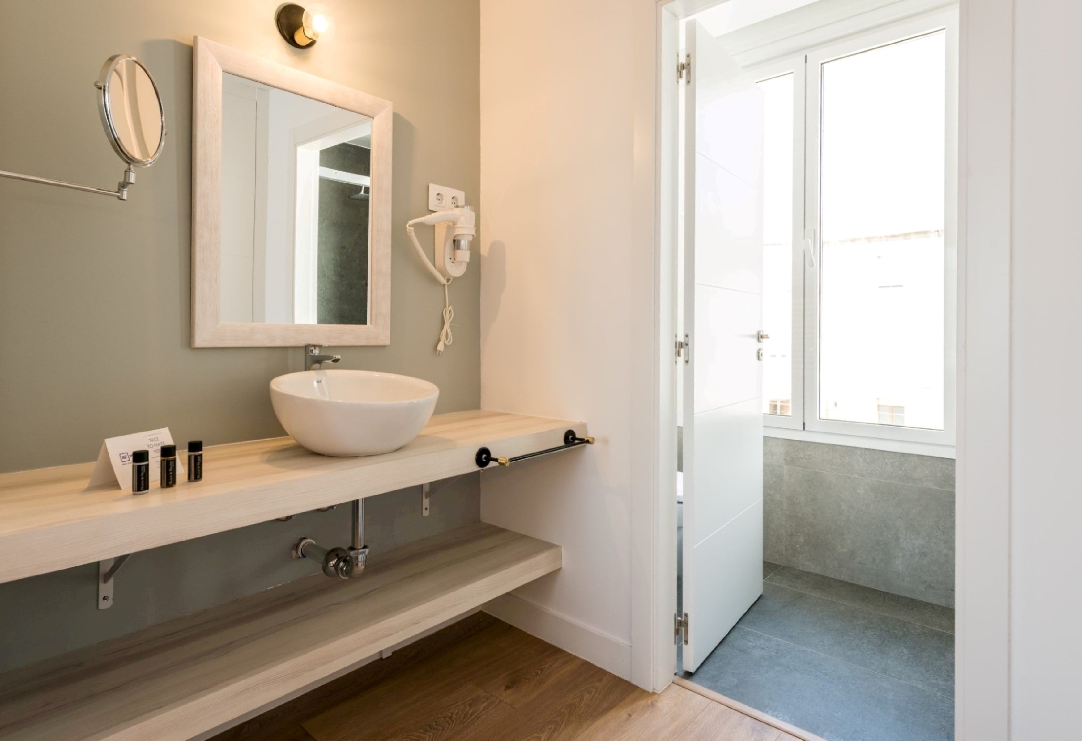 A modern bathroom with a large mirror, a white sink, and a towel rack.