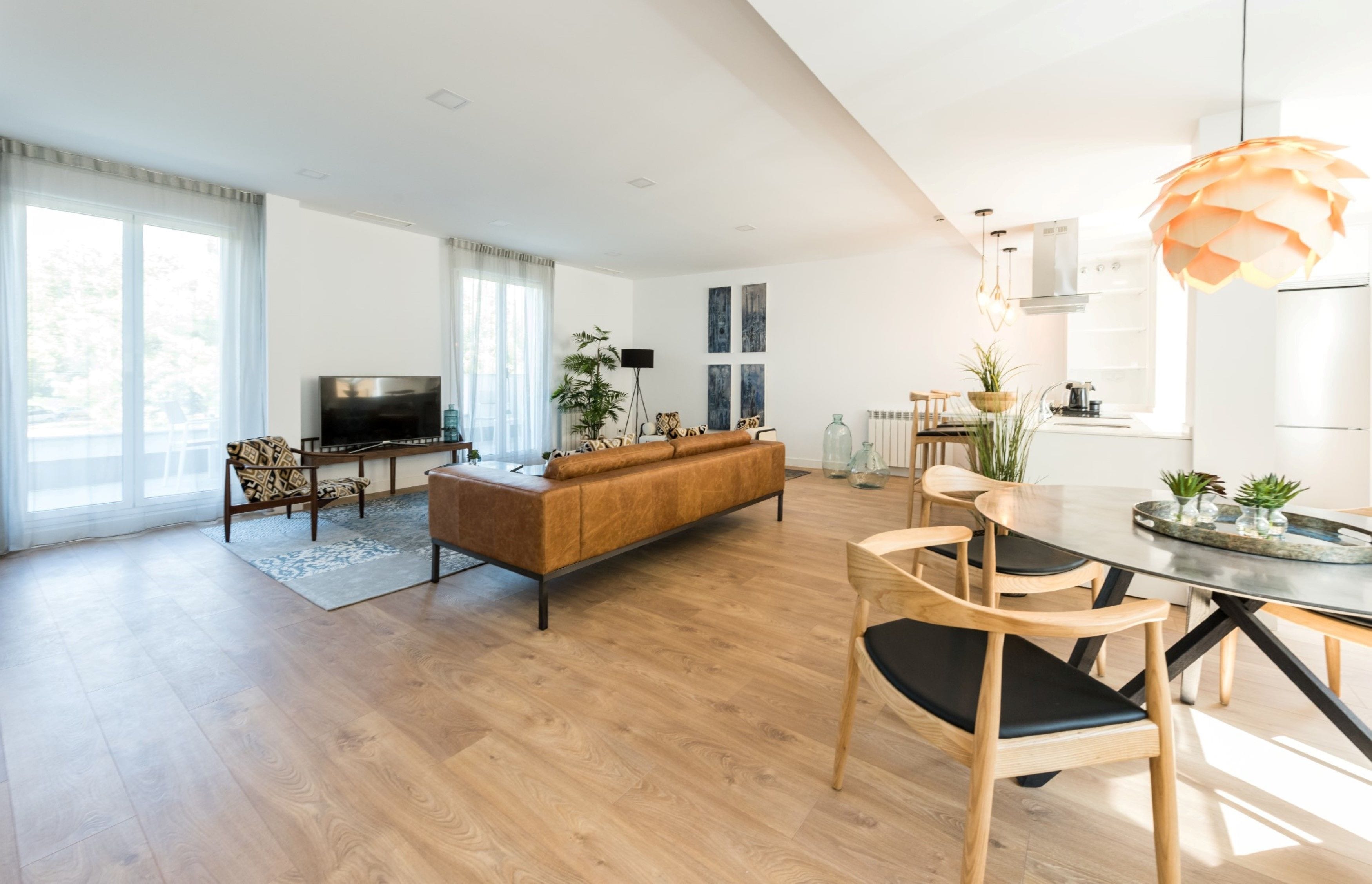 Una sala moderna con sofá, televisor y comedor.