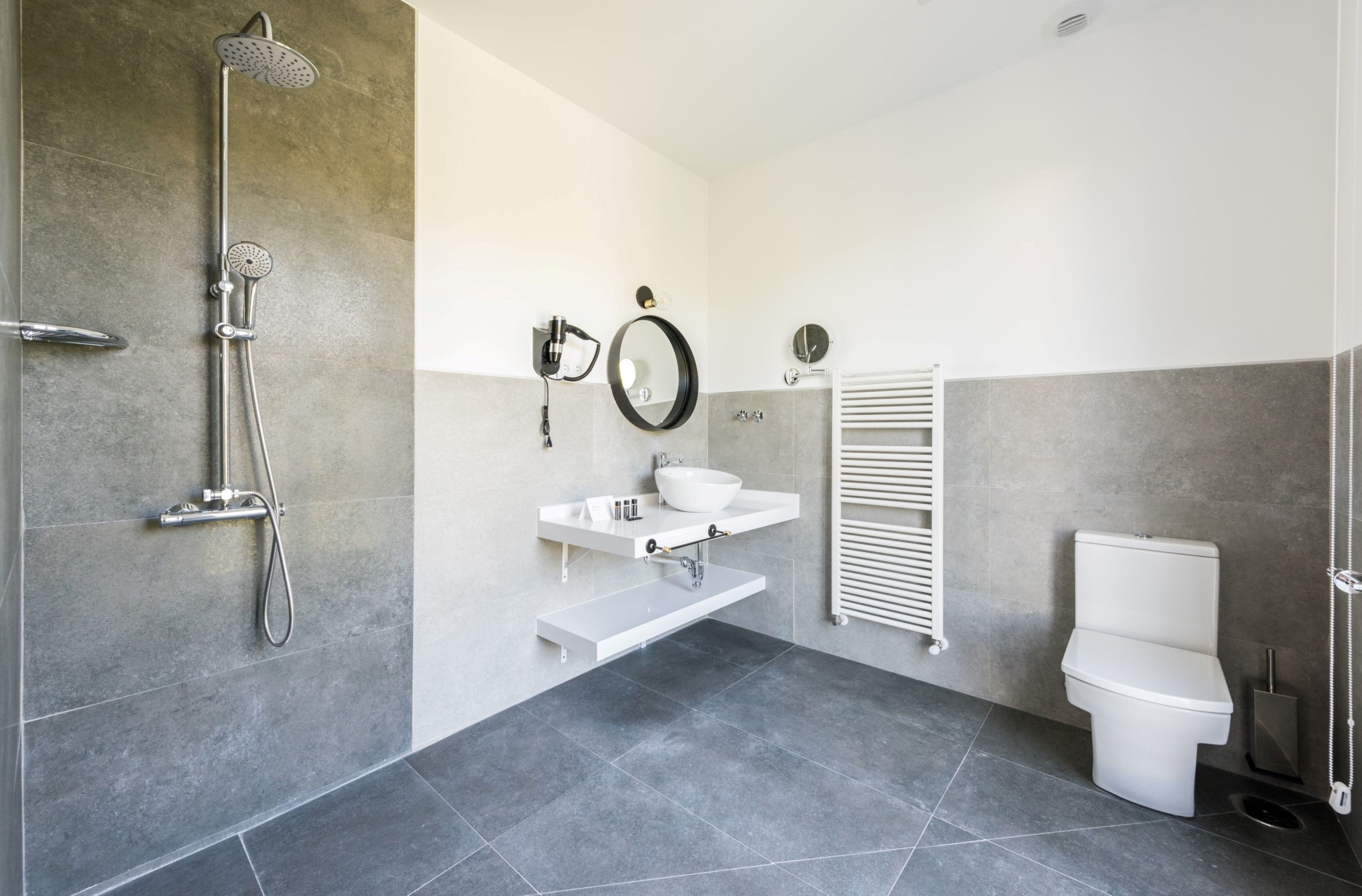 A modern bathroom with a shower, toilet, sink, and towel rack.