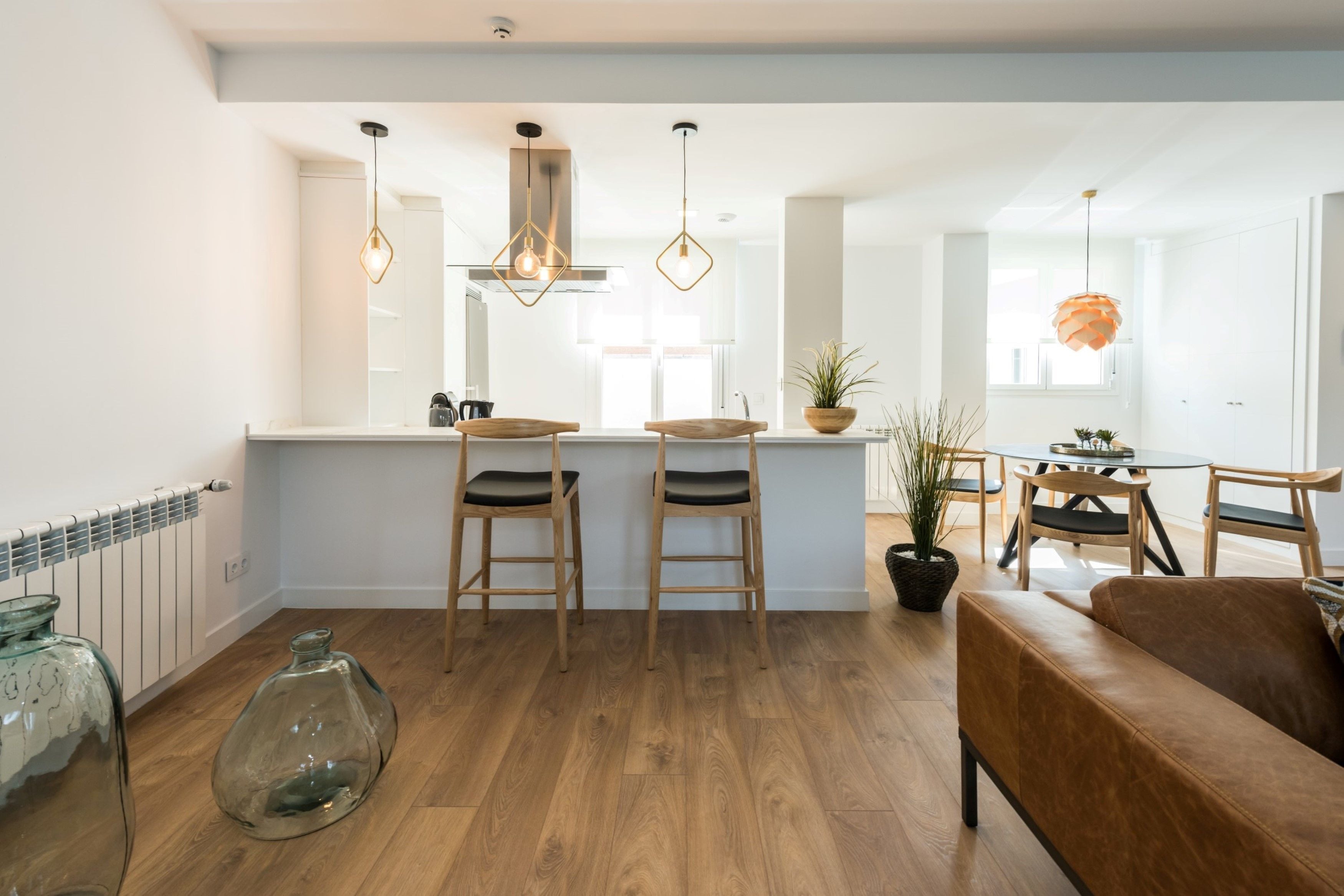Una cocina moderna con taburetes de madera, iluminación colgante y una isla central.