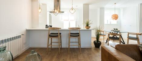 Una cocina moderna con taburetes de madera, iluminación colgante y una isla central.