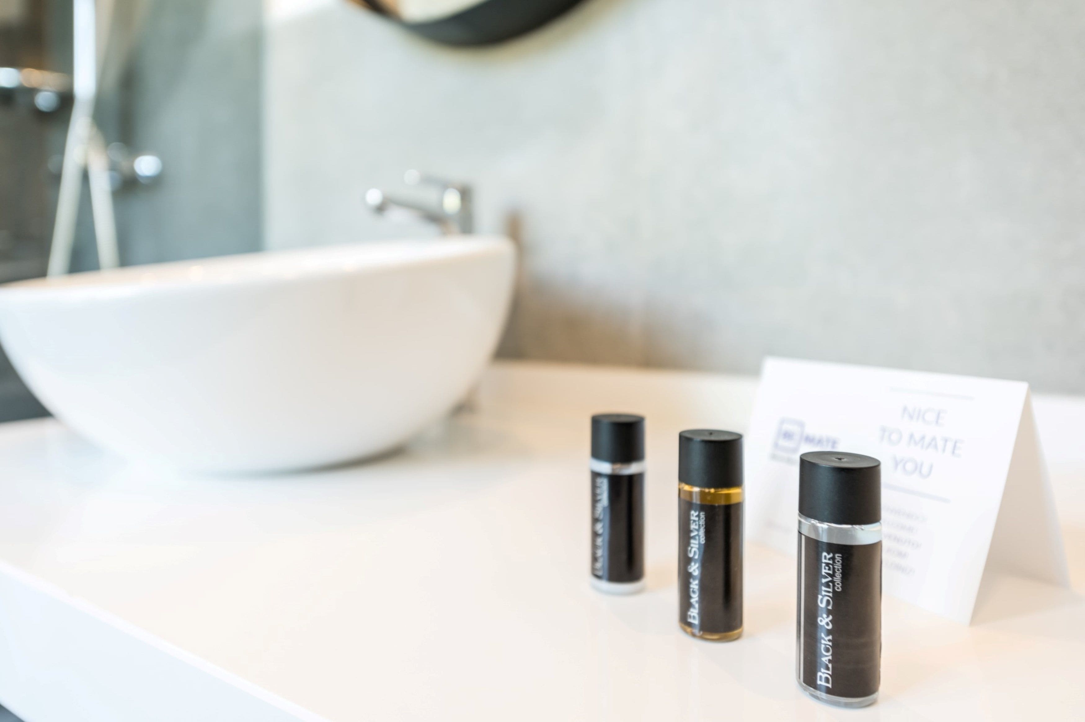A bathroom sink with three cosmetic containers and a sign.