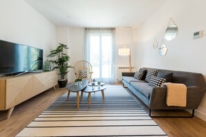 Una sala de estar moderna con un televisor de pantalla plana, un sofá, una mesa de centro y un tapete a rayas.