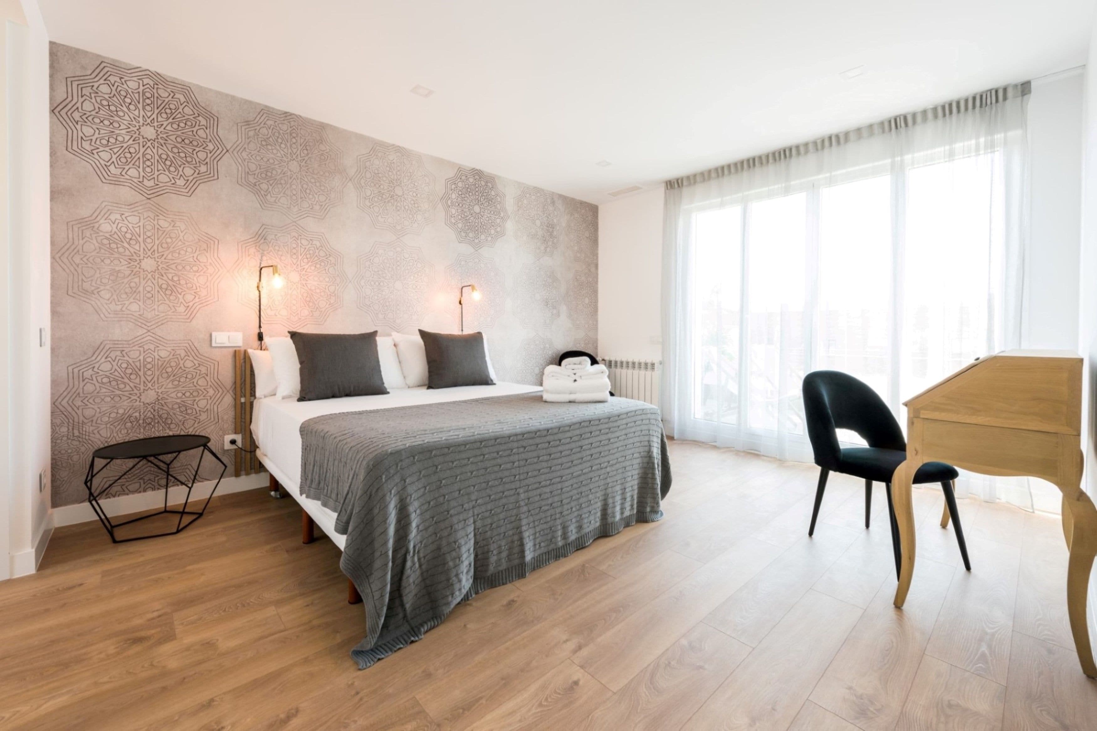 A modern hotel room with a large bed, a desk, and a view of the city.