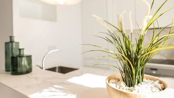 A modern kitchen with a wooden bowl containing a plant on the counter, a sink, and green glass containers.