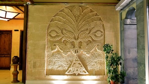Un hall d’entrée avec un grand mur décoratif, une plante en pot et une porte en bois.