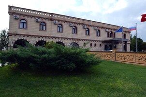 A historic building with arched windows and a flagpole with two flags.