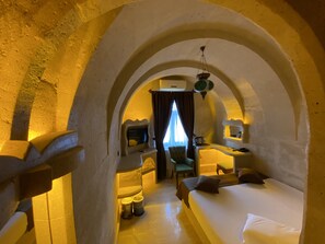 A cozy, arched room with a bed, a chair, a desk, and a television. - Alp Hotel Cappadocia (Avanos)