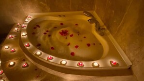 Un jacuzzi circulaire doté de lumières en forme de cœur et de pétales de rose.