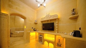 Une pièce aménagée comme un espace de bien-être, avec un mur en pierre, un téléviseur à écran plat, un petit réfrigérateur et un vase décoratif.