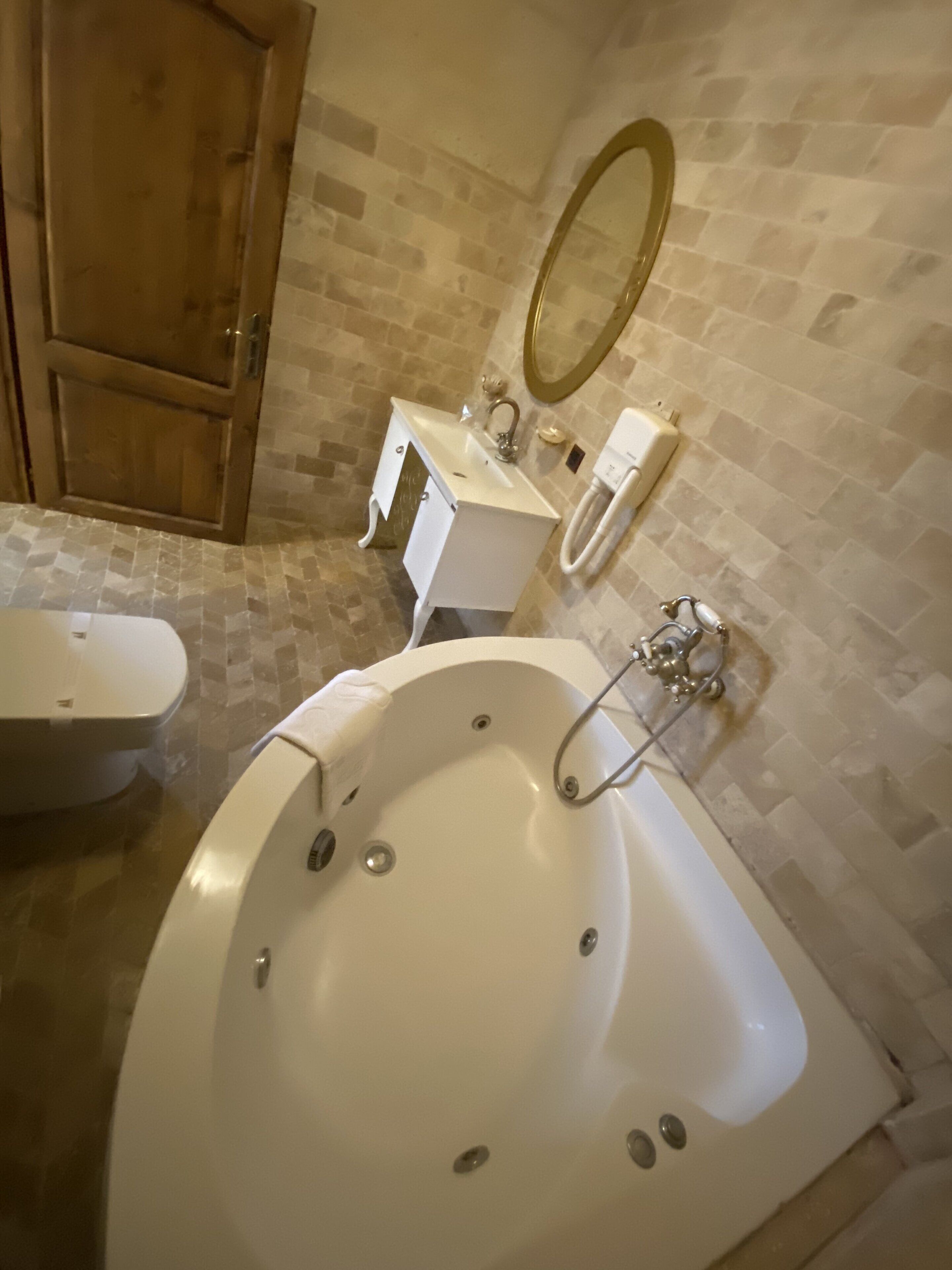 Ein Badezimmer mit einer freistehenden Badewanne, einer Toilette, einem Waschbecken mit Spiegel und einem Waschtisch.